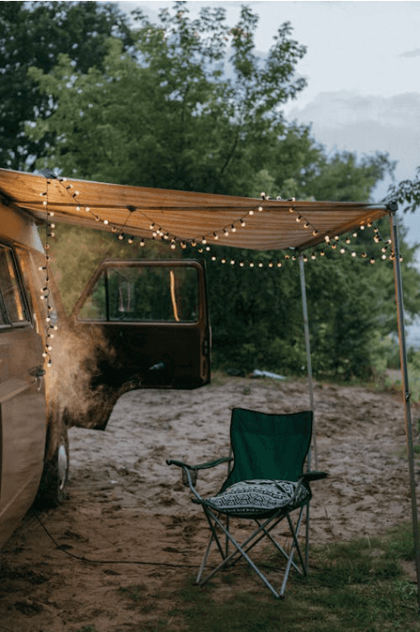 Evening campervan setup with fairy lights and folding chair under awning — creating a warm and relaxing van life atmosphere.
