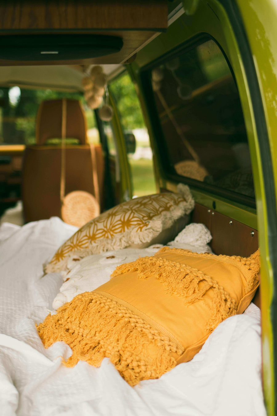Cosy campervan interior with mustard yellow cushions and soft bedding, relaxing van life setup for weekends away.