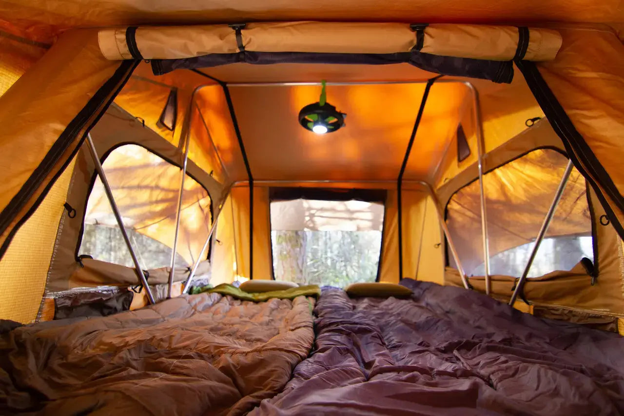 Inside view of a TentBox roof tent showing spacious sleeping area, padded bedding, and built-in LED light, highlighting interior comfort and design quality for off-grid camping.